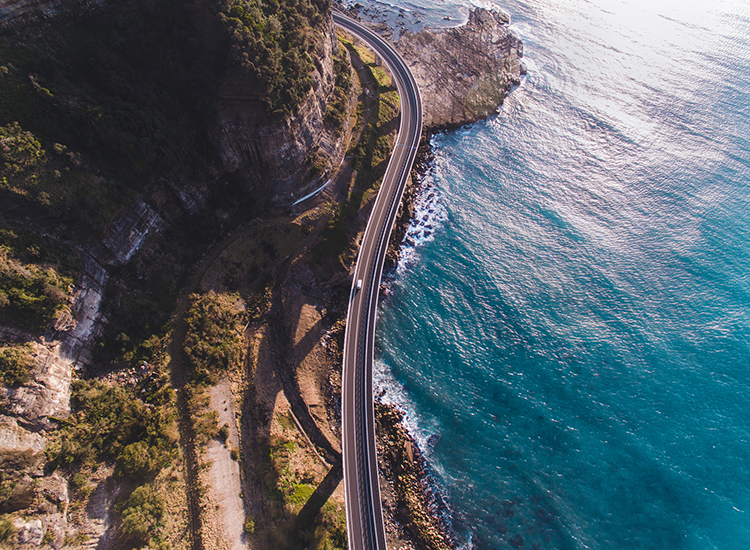 Overhead photo of bridge running along coast on a sunny day